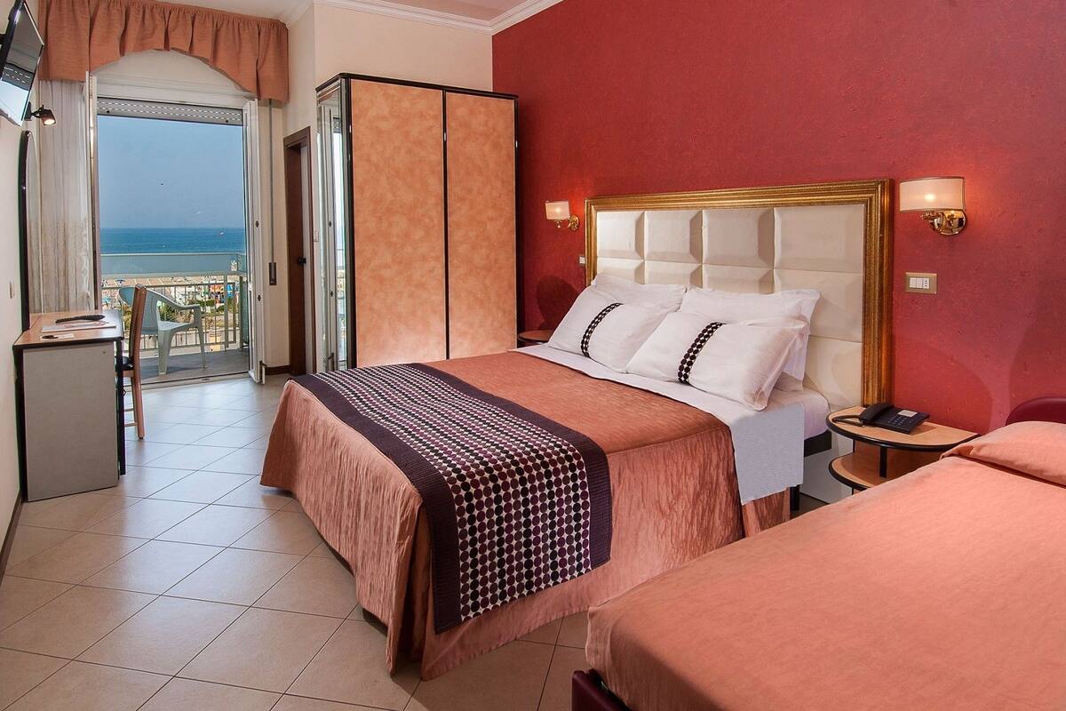 Ein Hotelzimmer mit Bett, Schreibtisch und Meerblick.