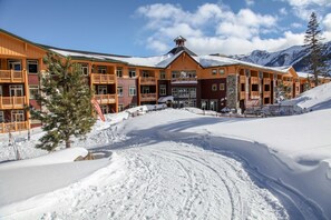 Een meerlaags hotel met balkons, een skipiste op de achtergrond en besneeuwde omgeving.