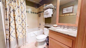 Een badkamer met douche, bad, toilet en wastafel met een spiegel.