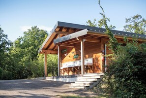 A wooden pavilion with a sloped roof, outdoor sinks, and a fire extinguisher. - Huttopia Royat (Royat)