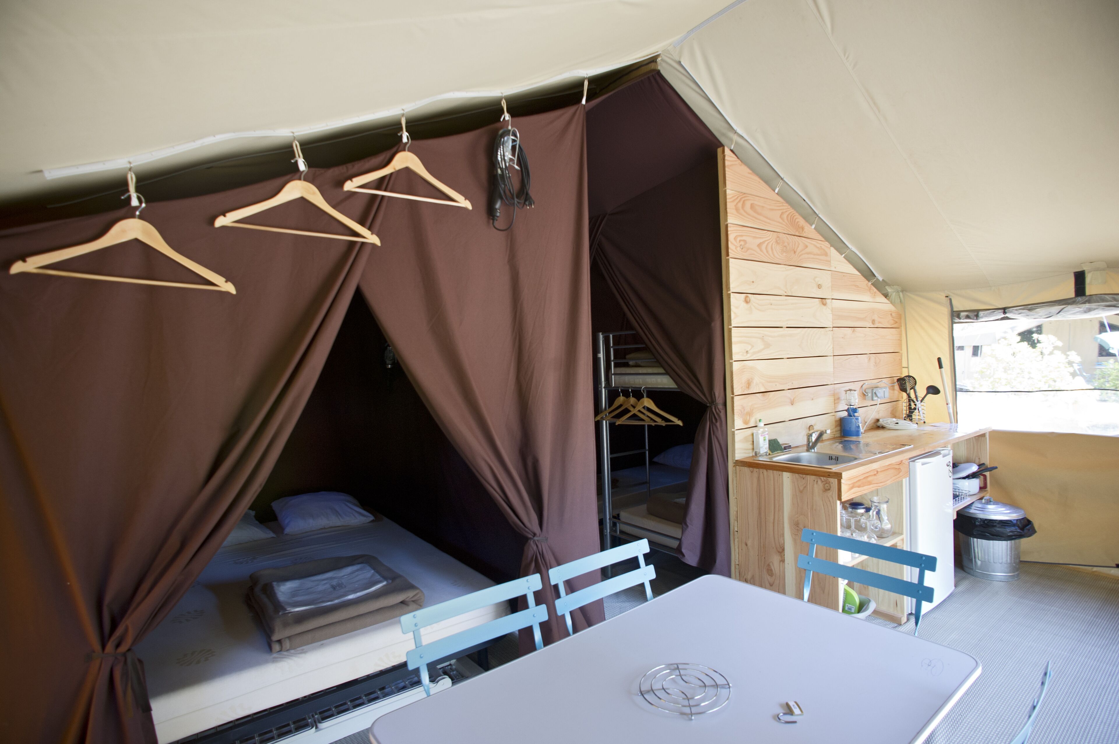 Alojamiento con tienda de campaña, cama, mesa y kitchenette.