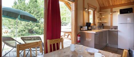 A wooden dining table with chairs, a red curtain, and a view of the outdoors.