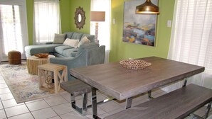 A dining area with a wooden table, benches, and a woven basket. - Windancer Cottages by Crystal Waters (Destin)