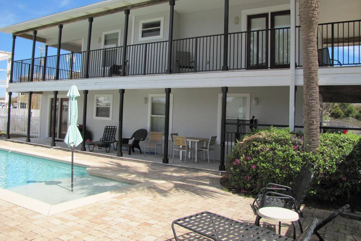 A two-story building with a pool, outdoor seating, and a balcony.
