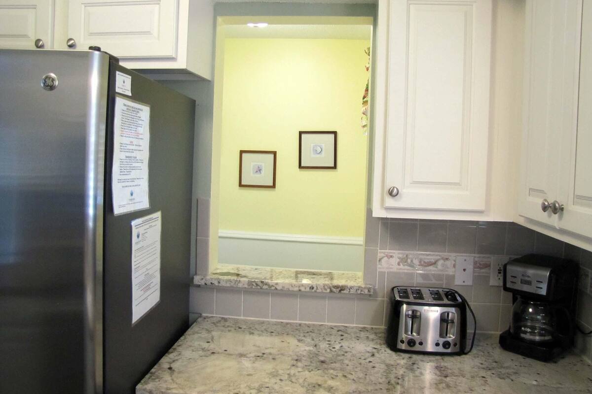A kitchen with white cabinets, a stainless steel refrigerator, a toaster, and a coffee maker.