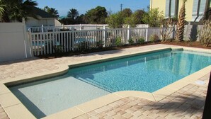 A rectangular swimming pool with a tiled edge, surrounded by a brick patio. - Windancer Cottages by Crystal Waters (Destin)
