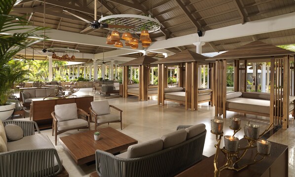 A spacious indoor area with seating arrangements, ceiling fans, and hanging light fixtures.