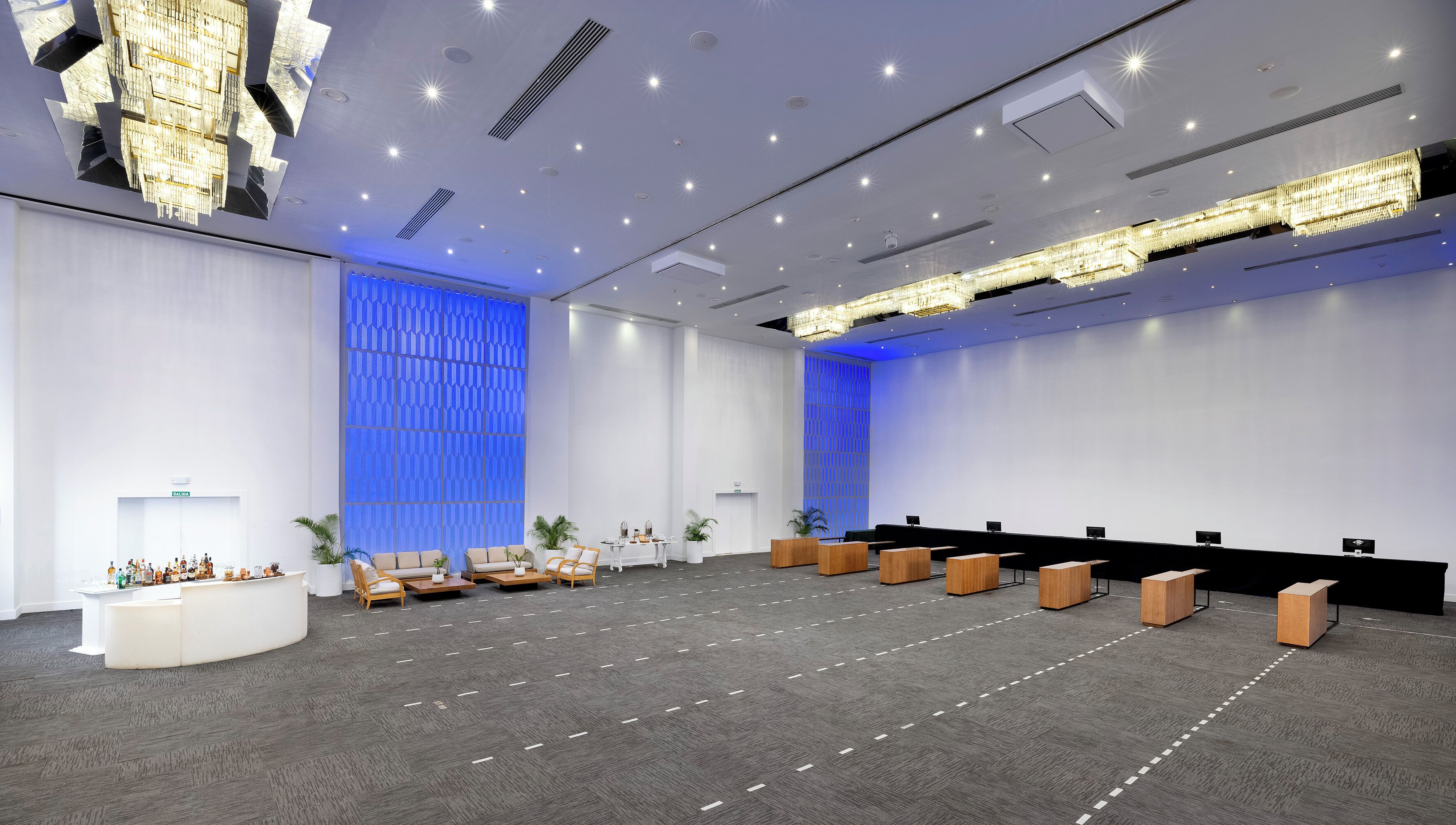 A spacious conference room with a high ceiling, recessed lighting, and a modern chandelier.