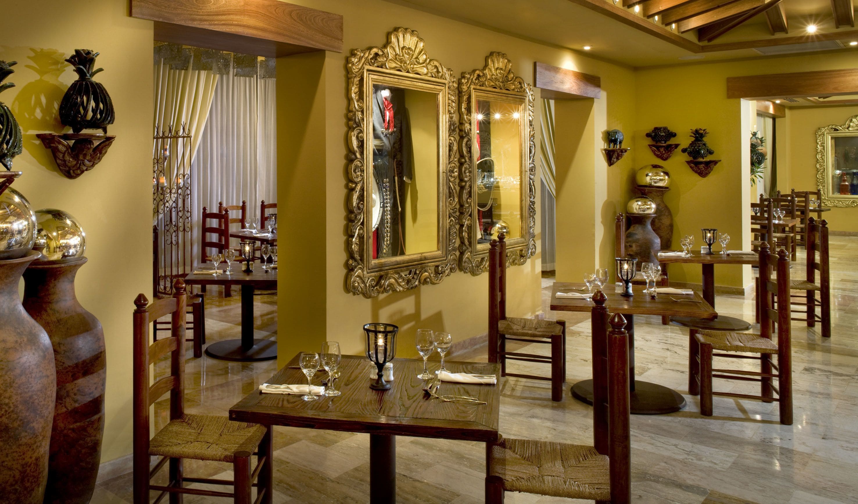 A dining area with ornate mirrors, wooden furniture, and a polished floor.