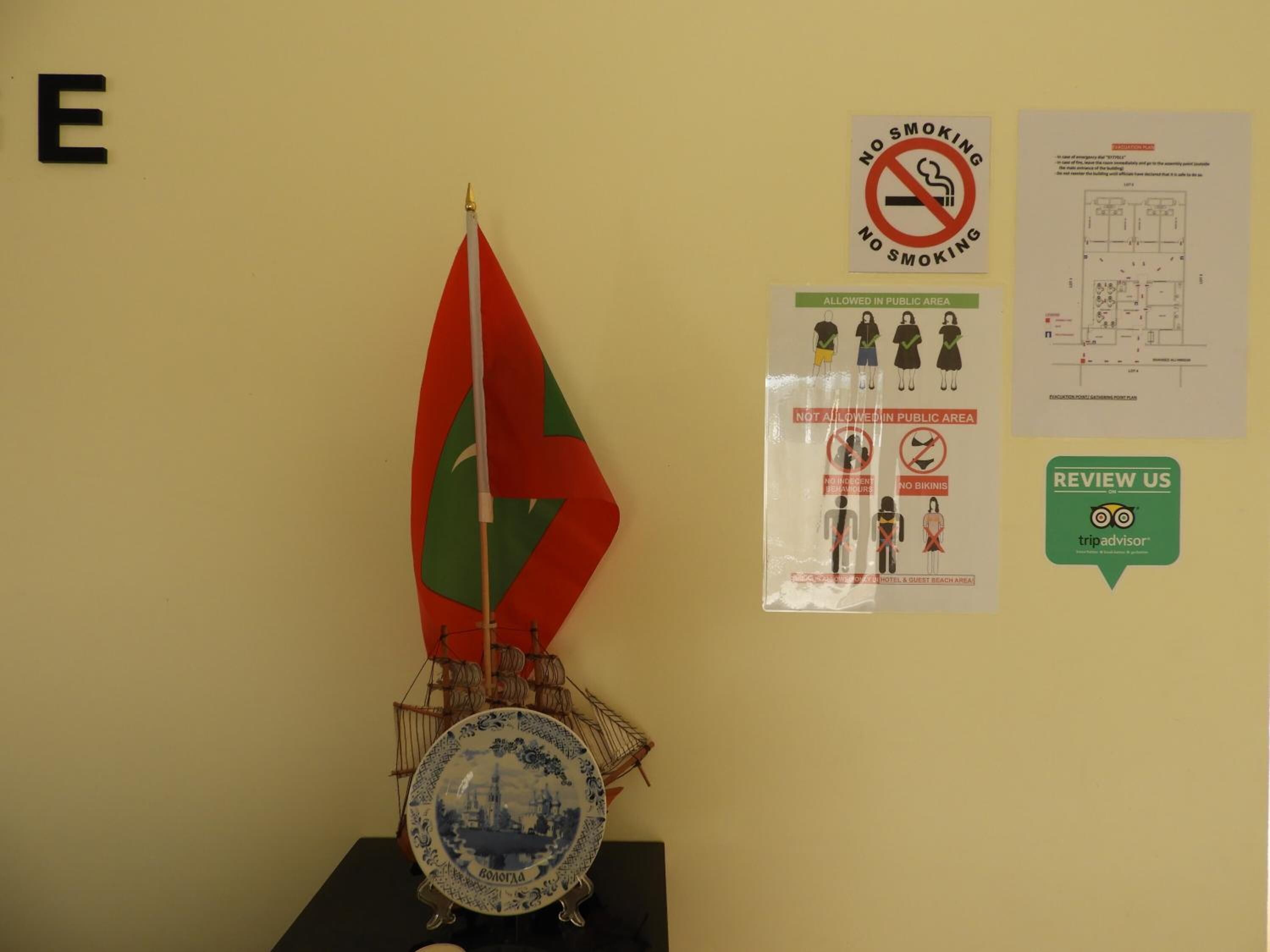 A wall with a large letter 'E', a no smoking sign, a poster with public area rules, a map, and a TripAdvisor badge.