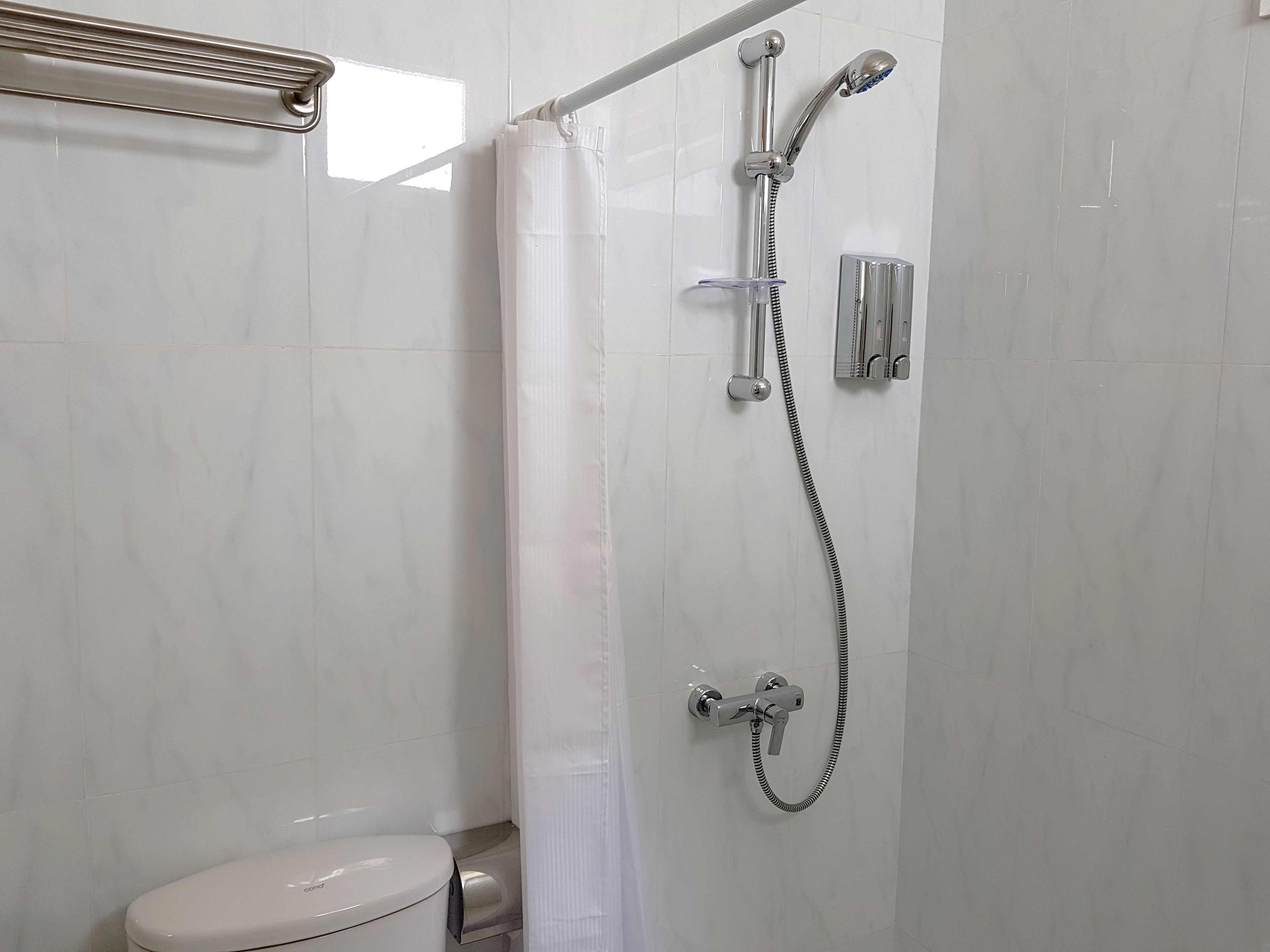 A bathroom with a shower, toilet, and a towel rack.