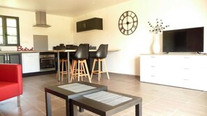 Una cocina moderna con comedor, una silla roja y un televisor de pantalla plana.