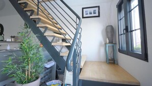 Un escalier avec des finitions en bois et des rampes noires, une plante en pot, une petite table et une fenêtre donnant sur un beau paysage.