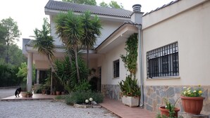 A house with a tiled roof, a covered porch, and a gravel driveway. - Casa Rural Aire (Muro del Alcoy)