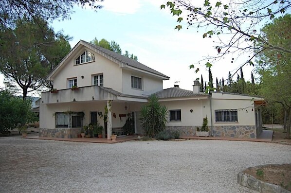 Uma casa de dois andares com varanda coberta e base de pedra.
