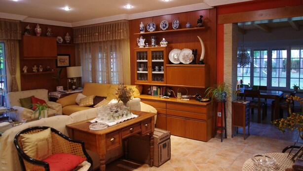 Una sala de estar bien iluminada con un sofá, una mesa de centro de madera y un comedor con mesa y sillas.