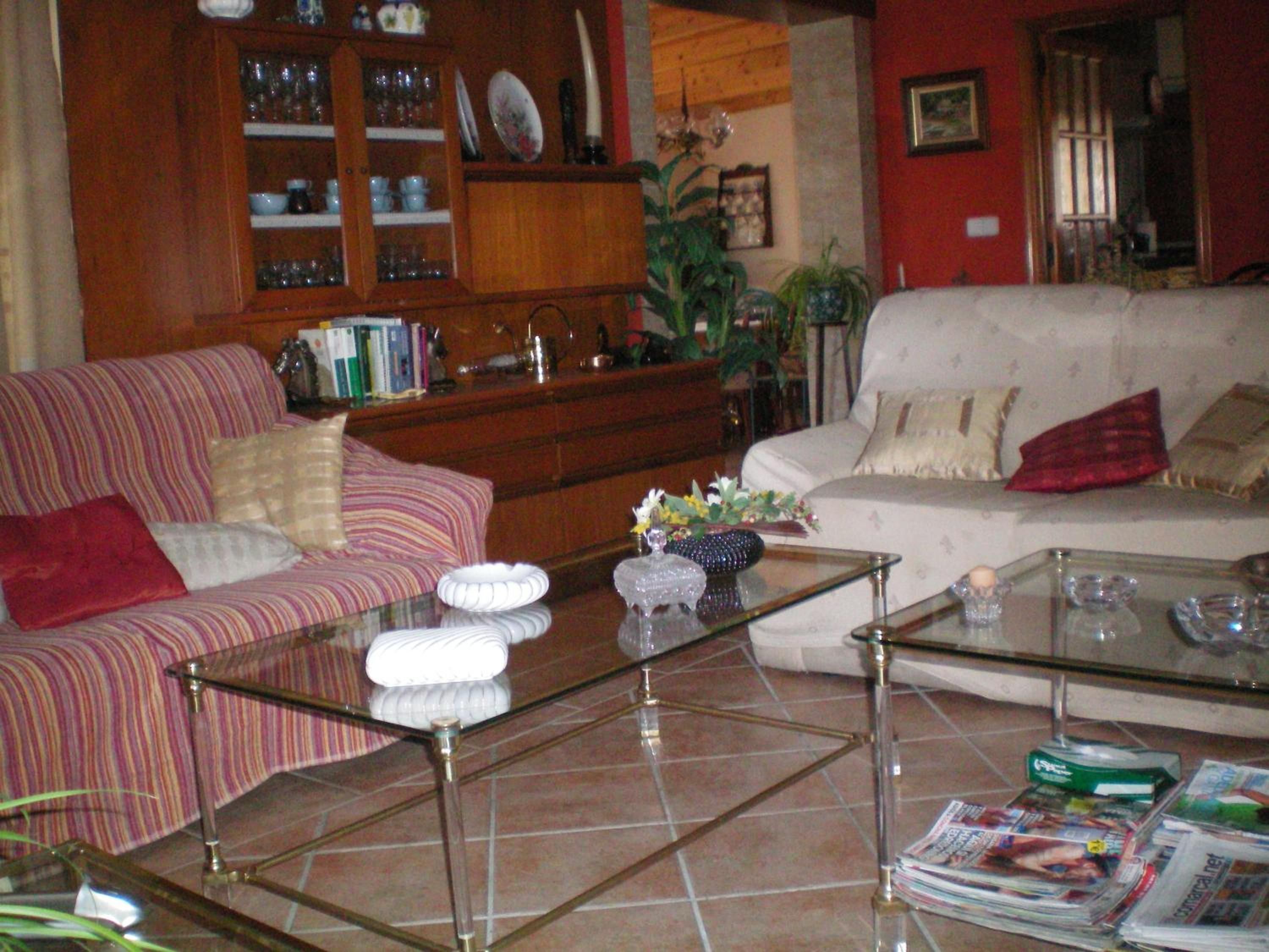 A living room with a striped sofa, a glass coffee table, and a bookshelf filled with books and decorative items.