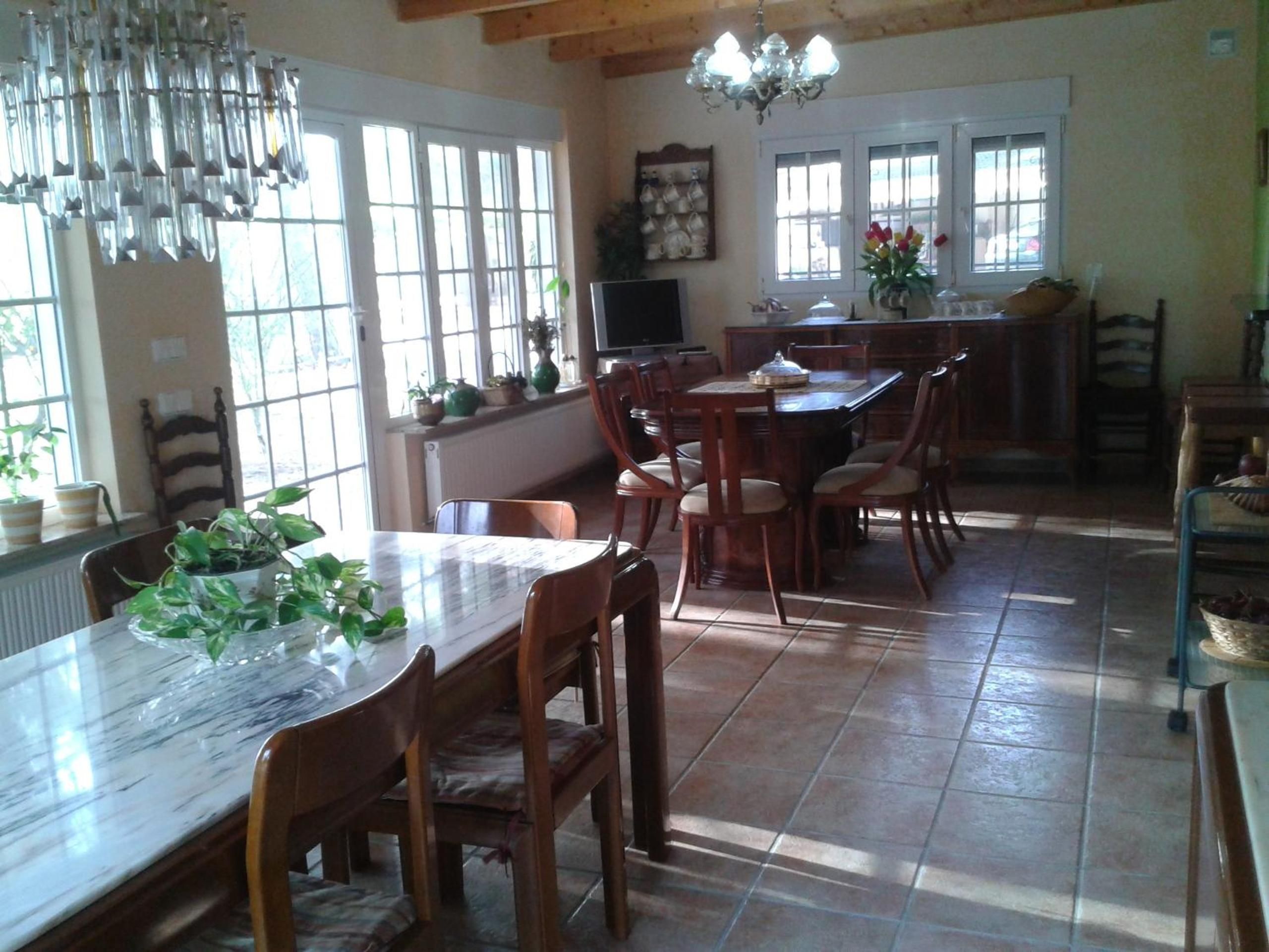 A dining area with a marble table, wooden chairs, and a chandelier.