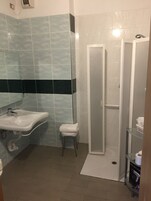Un baño con lavamanos, espejo, ducha y un taburete pequeño.
