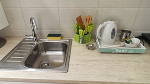 A kitchen with a stainless steel sink, a green utensil holder, a white kettle, and a box labeled "Beer". - Apartments Top Central 2 (Belgrade)