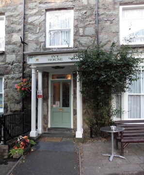 Edificio de piedra con una puerta verde que indica 'Vacaciones' y un cartel arriba que dice 'Ivy House'.