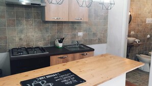 A modern kitchen with wooden cabinets, a gas stove, and pendant lights.