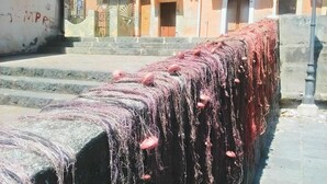 A stone wall with fishing nets and buoys.