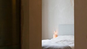 A bedroom with a single bed, a nightstand, and a hanging light fixture.
