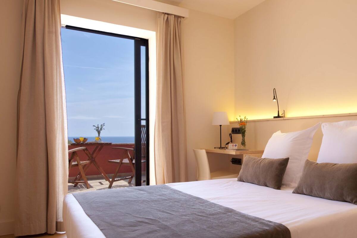 Une chambre d’hôtel avec un grand lit, un bureau et une vue sur la mer.