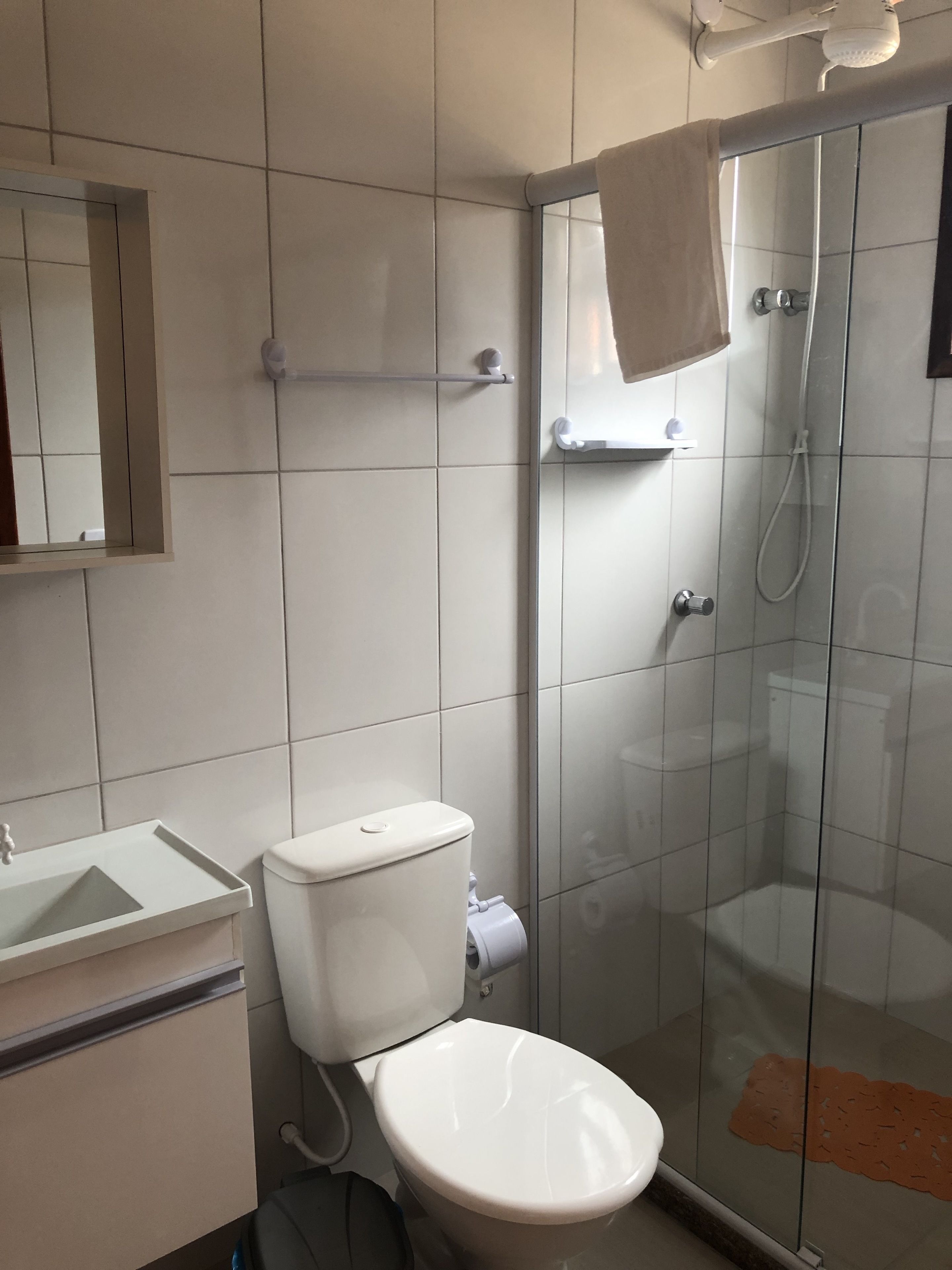A bathroom with a toilet, sink, and glass shower enclosure.