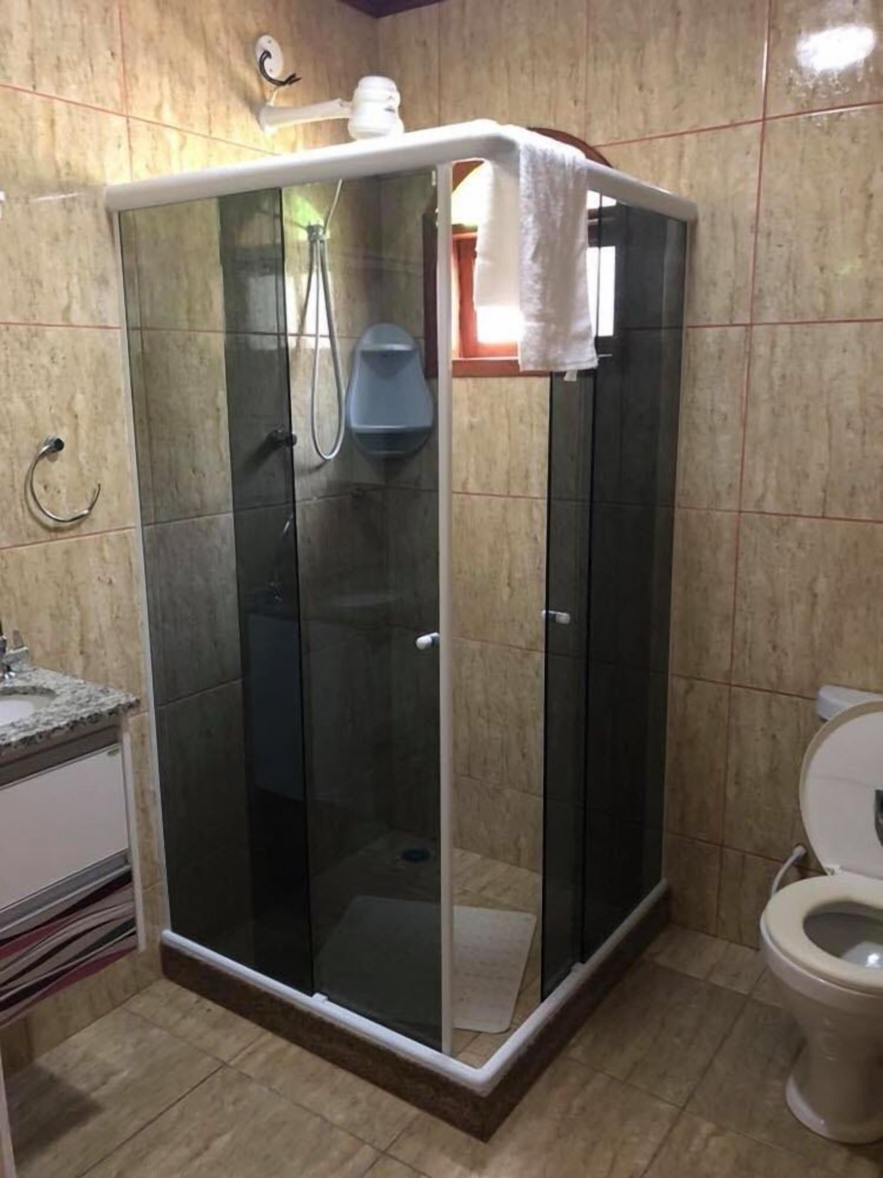 Un baño con ducha corredera de vidrio, inodoro y lavamanos.