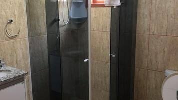 Un baño con ducha corredera de vidrio, inodoro y lavamanos.