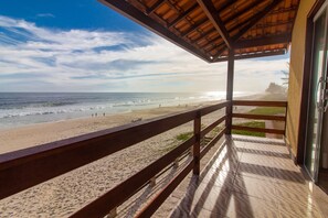 A beach view from a covered balcony with a wooden railing and tiled floor. - Black Point Beach Club (Marica)