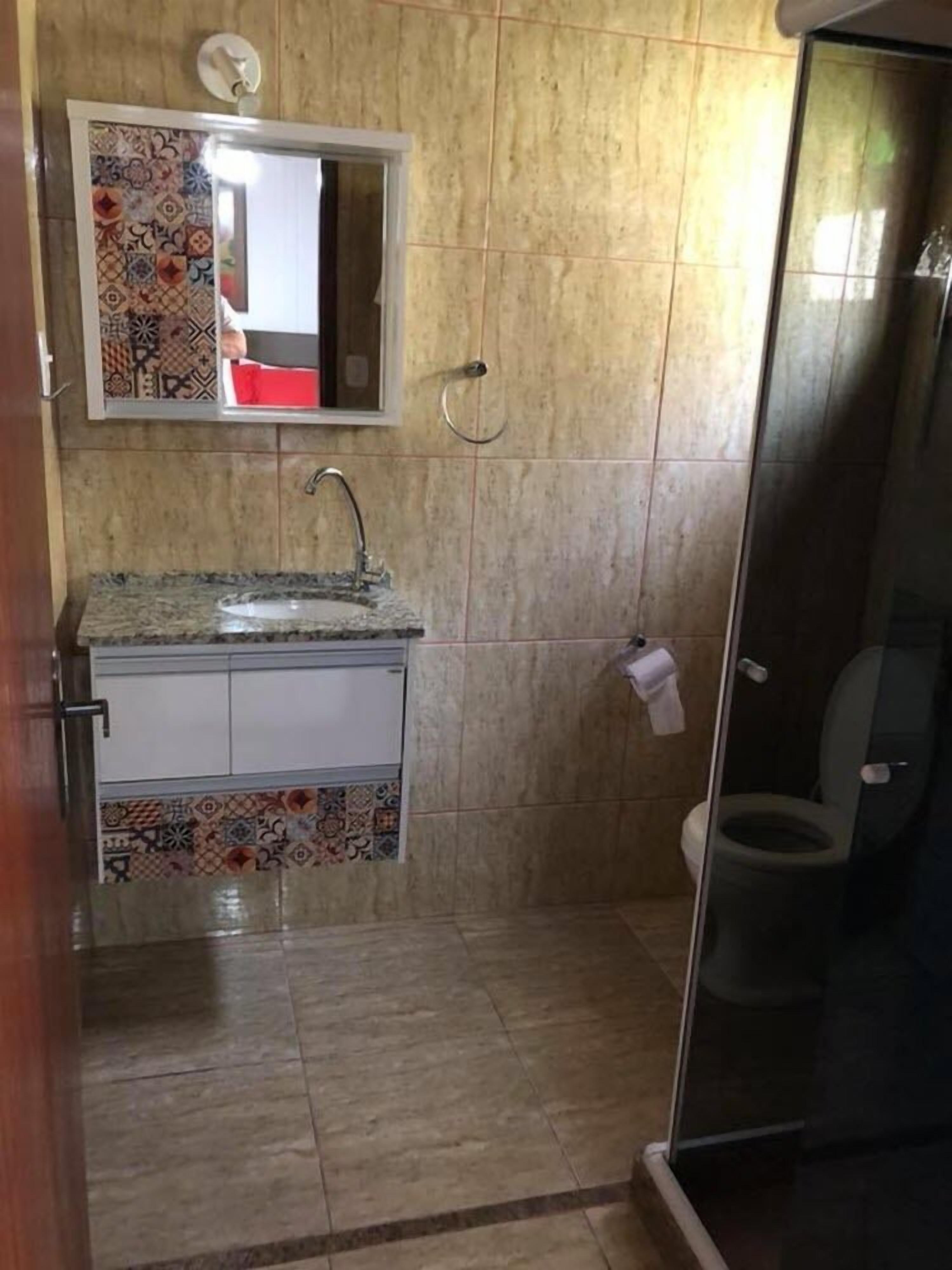 A bathroom with a tiled floor, a sink with a faucet, a toilet, and a shower area with a glass door.