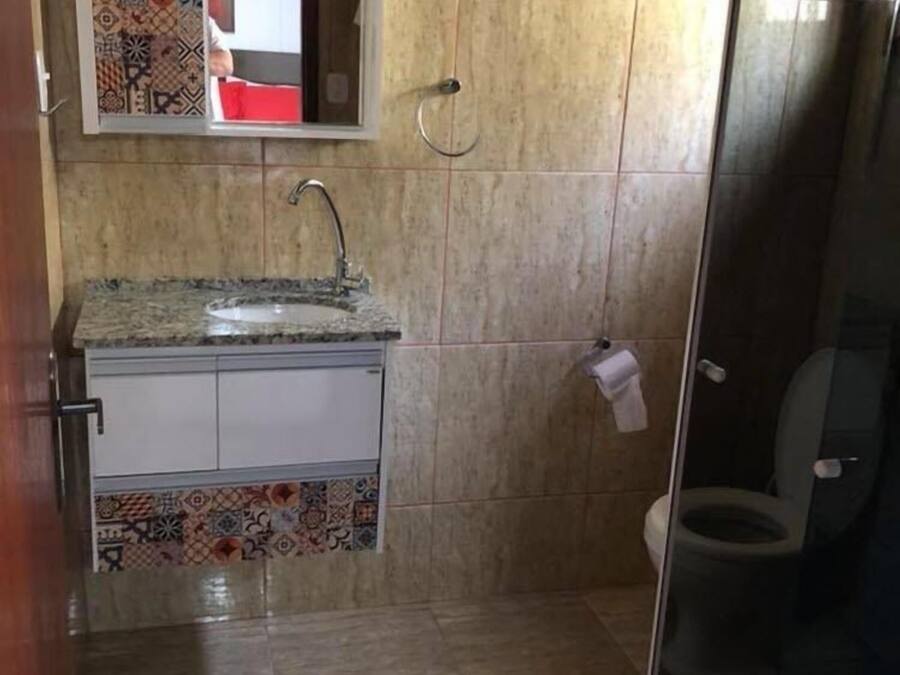 A bathroom with a tiled floor, a sink with a faucet, a toilet, and a shower area with a glass door.