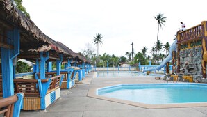 Un área de piscina con estructuras azules y marrones, un tobogán de agua y un cartel que dice "Royal Grand".