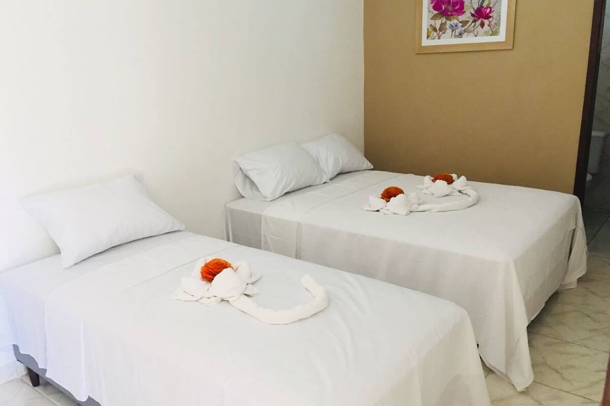 Two single beds with white linens and a floral arrangement on each.