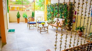 A patio area with a seating arrangement, potted plants, and a decorative wall. - Pousada Costa Dourada (Ipojuca)