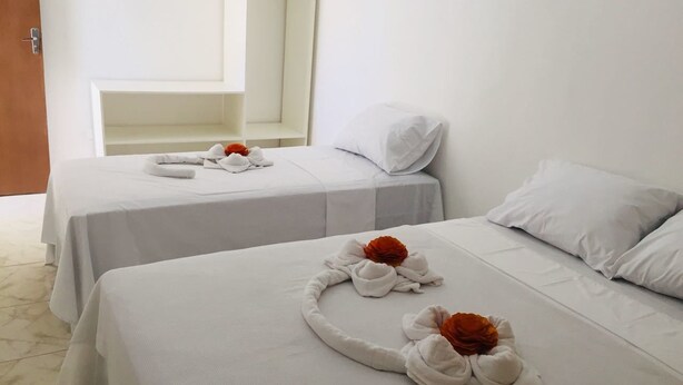 Two single beds with white linens and towels arranged in a circular pattern. - Pousada Costa Dourada (Ipojuca)