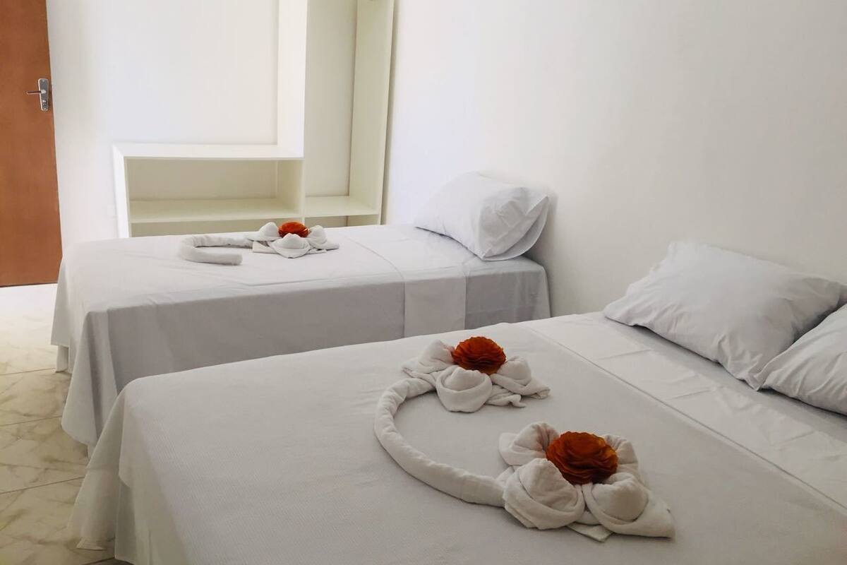 Two single beds with white linens and towels arranged in a circular pattern.