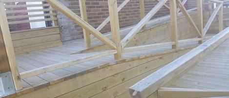 A wooden staircase with a metal railing, leading to a brick wall.