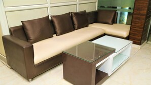 A brown leather sofa with a glass coffee table in a room with tiled flooring. - Hotel Suzi International (New Delhi)