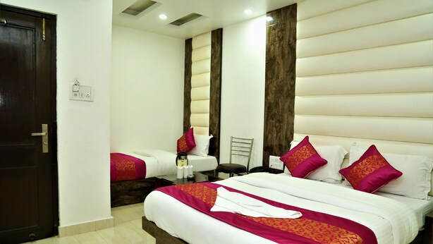 A hotel room with a large bed, a smaller bed, a desk, and a chair. - Hotel Suzi International (New Delhi)
