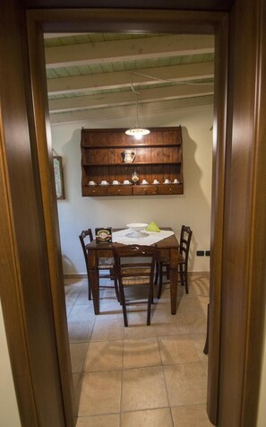 A dining area with a wooden table, chairs, and a hanging shelf above. - Michelangelo B&B (Lecce)