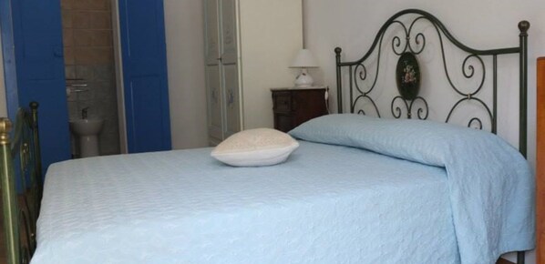 A bedroom with a bed, a nightstand, a lamp, and a wardrobe. - Casa Camilla (San Vito)