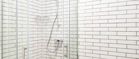 Un baño con cabina de ducha de vidrio, un inodoro y baldosas de suelo con diseño.