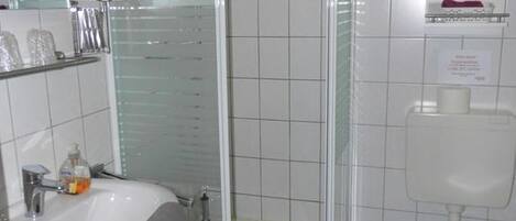 A bathroom with a glass-enclosed shower, a white sink, and a toilet.