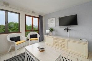 Una sala de estar moderna con un sofá, una mesa de centro, un televisor y un ventanal con vistas.