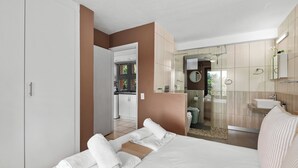 Quarto de hotel moderno com uma cama, banheiro e vista para a cozinha.