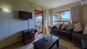 A living room with a TV, sofa, and coffee table. - San Lameer Villa Rentals One Bedroom Standard 10425 (Southbroom)